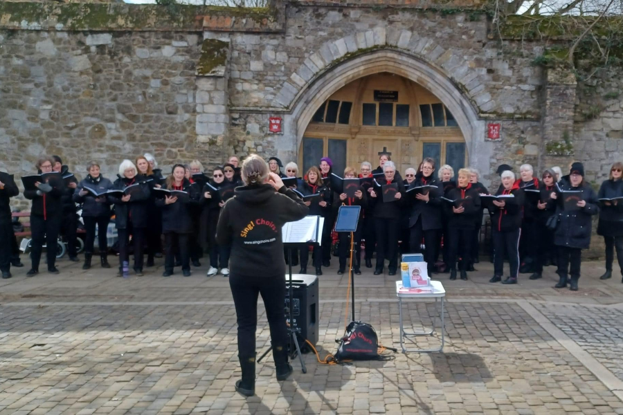Sing! Choirs Singing on Ely Market in March 2022, next to the War Memorial where we will be for our first performance of 2023!